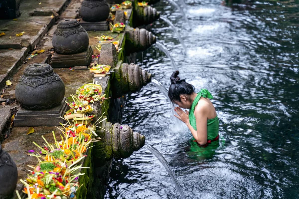 Woman praying and bathing in holy spring waters in Tirta Empul water temple in Bali