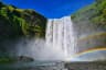 Beautiful-waterfall-with-rainbow-and-green-mountains-under-clear-blue-sky