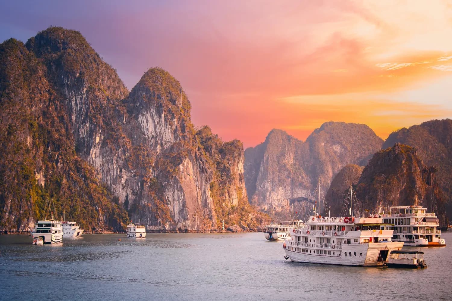 Scenic sunset over Halong bay, Vietnam with boats and limestone karsts