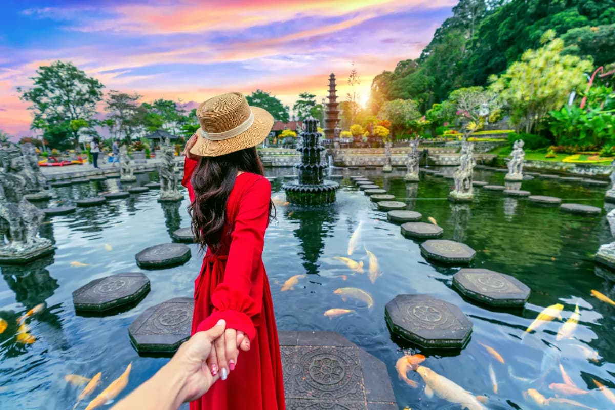 Women tourists holding man's hand and leading him to Tirta Gangga