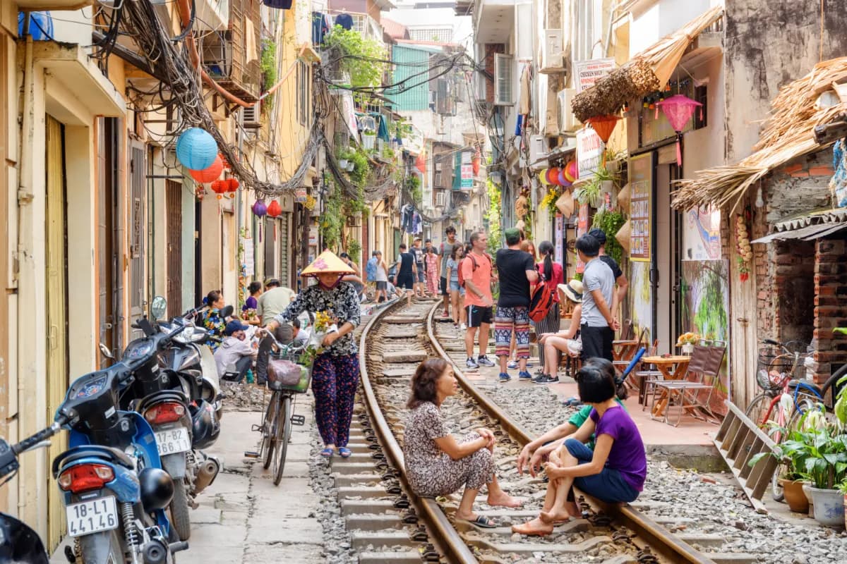 Vietnamese woman in traditional hat walking along a narrow street of the Hanoi Old Quarter