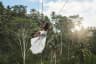 Young woman wearing white dress swinging on rope swings with beautiful view on rice terraces.