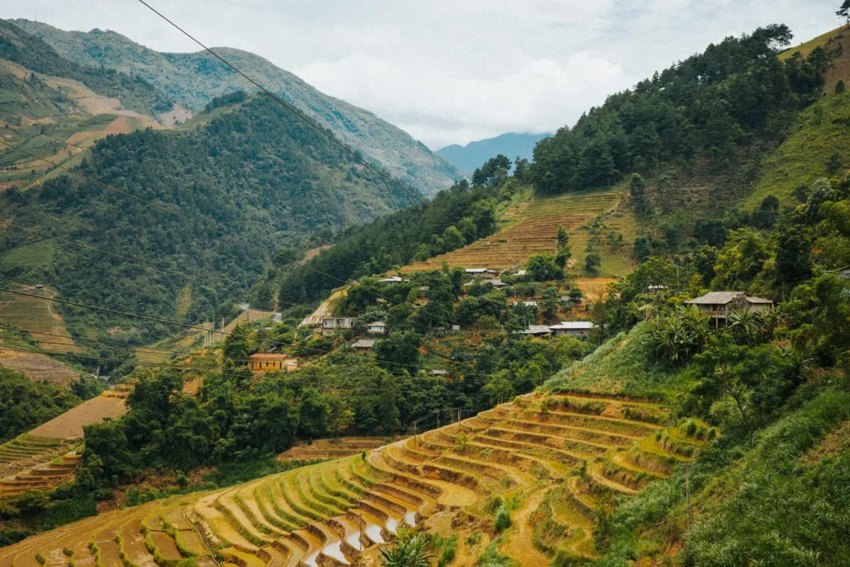 Lush green rice terraces cascade down vibrant hills, with rustic village homes in the distance